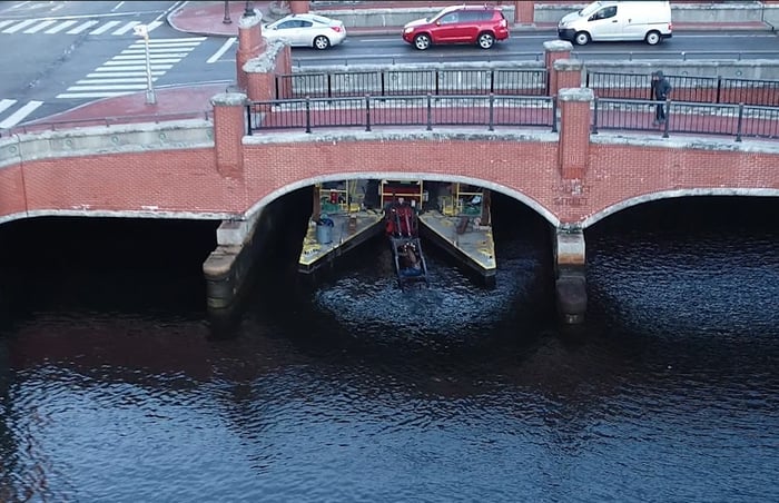 Small dredge under bridge during Woonasquatucket River restoration project