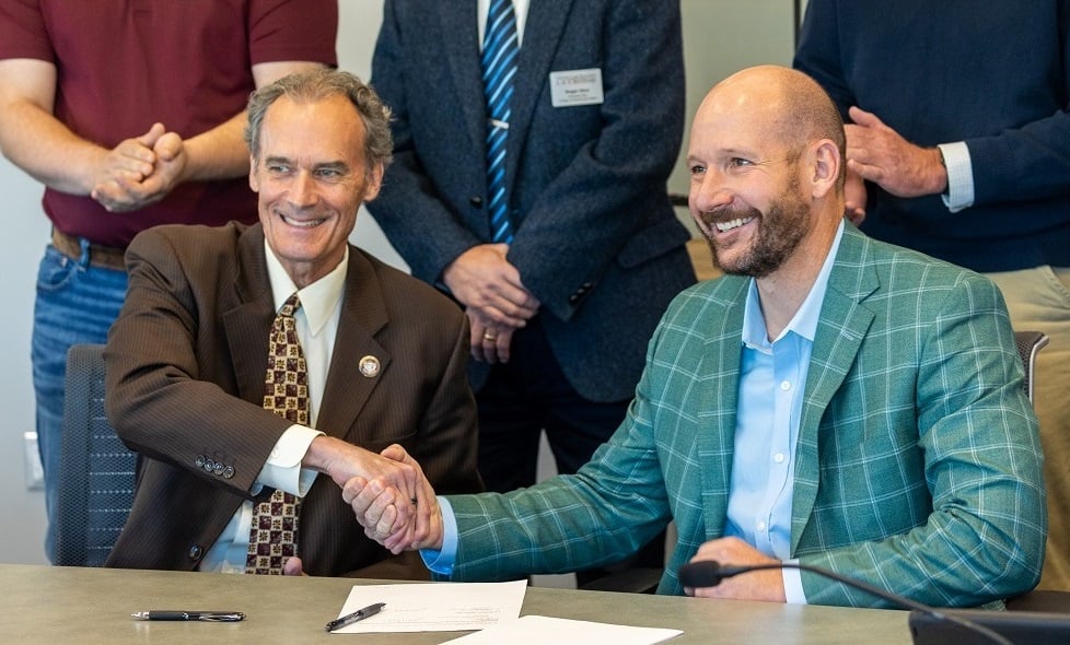 UWL Chancellor Joe Gow and Brennan President and CEO Matt Binsfeld formalizing the partnership between their organizations.